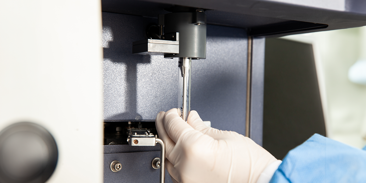 Scientist loading a test tube containing a patient sample on the flow cytometer for analysis