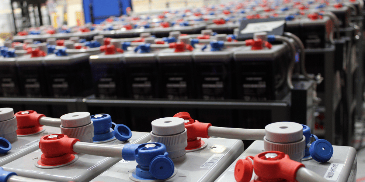 A large stack of batteries organized neatly in a warehouse setting, showcasing an extensive inventory.