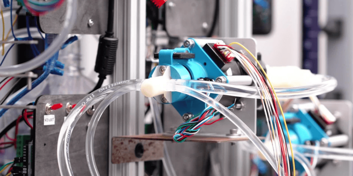 Close-up of mechanical assembly with blue component, clear tubing, and colorful wiring