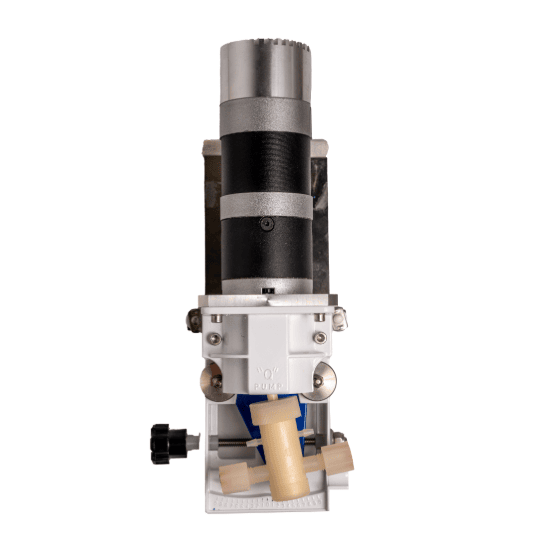 Close-up view of a mechanical pump device with a cylindrical black and metallic motor, white housing, beige pump head, and a black adjustment knob