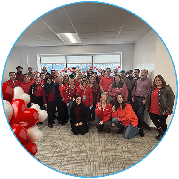 A group of people in an office wearing red tops, posing for a group photo in front of a decorated window.