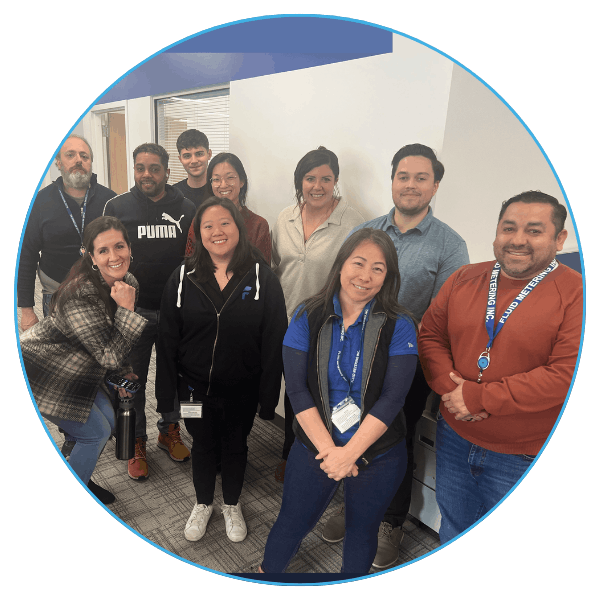 A group of ten diverse people in casual clothing smiling in an office setting, conveying a friendly and collaborative atmosphere.