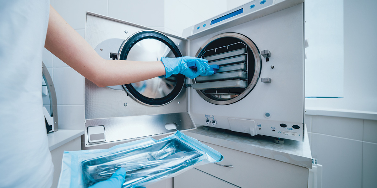 Lab worker taking out disinfected medical equipment from machine