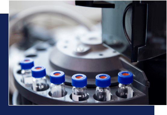 Close-up of a laboratory carousel holding several small vials with blue caps