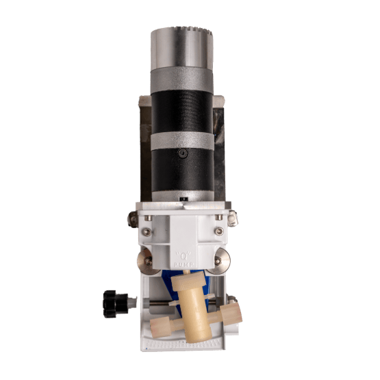Close-up view of a mechanical pump device with a cylindrical black and metallic motor, white housing, beige pump head, and a black adjustment knob